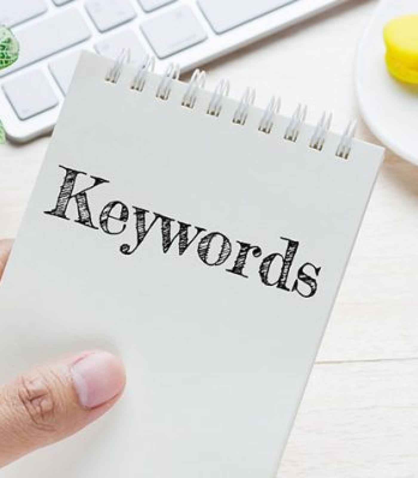 Hand holding a piece of paper with the word 'Keyword' written on it, symbolizing keyword research in SEO